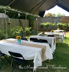 an outdoor dining area with tables and chairs set up for dinner in the back yard