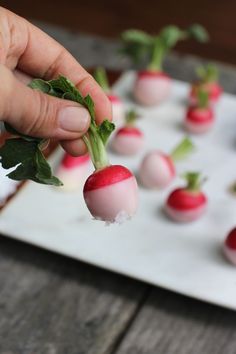 a person is picking up some radishes from a tray with other radishes on it