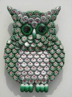 an owl made out of green and white buttons with large eyes sitting on top of a wall