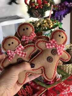 someone holding up some gingerbread man ornaments