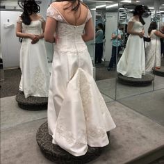 a woman standing in front of a mirror wearing a wedding dress