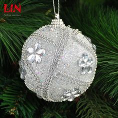 a christmas ornament hanging from a tree with snow flakes and crystals on it