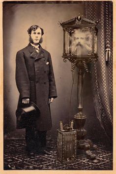 an old time photo of a man standing next to a lamp and other items in front of him