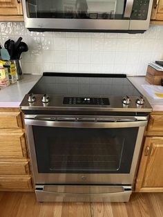 a stainless steel oven in a kitchen with wooden cabinets and white tile backsplash