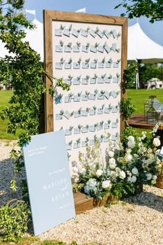 an outdoor ceremony with flowers and a sign for guests to place their names on the wall