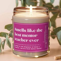 a candle that reads smells like the best mentor teacher ever on it next to some leaves