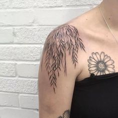 a woman's shoulder with a flower and bamboo leaves tattoo on it, next to a brick wall