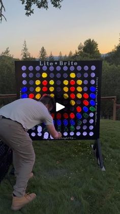 a man standing in front of a giant board game on top of a grass covered field