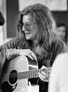 black and white photograph of a woman playing an acoustic guitar in front of a man