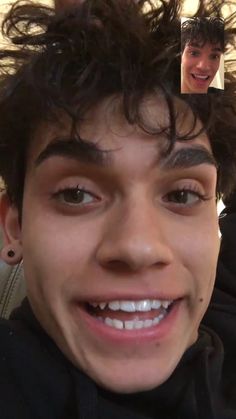 a young man with curly hair is smiling at the camera and has his head shaved back