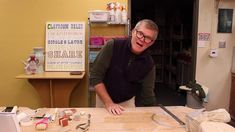 a man standing in front of a wooden table with scissors and other items on it