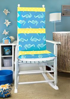 a white rocking chair with blue and yellow fabric on it in a child's room