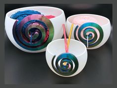 three bowls with yarn in them sitting on a black counter top next to each other