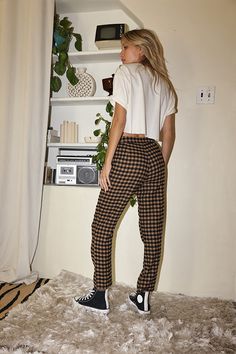 You are the trend setter in the Bishop Tan Checkered Cropped Trousers. Made with everyone's favorite checkered print and a straight leg fit, these are the pants you have been searching for! Style with a cropped tee or a chunky sweater, you will be able to rock these trousers in every way imaginable. STYLE RECOMMENDATIONS: - pair with some high tops and a cropped tee for a casual look, or spice it up with some wrap sandals and statement earrings SIZE RECOMMENDATIONS & MATERIALS: - light weight t 70s Tomboy, Early Fall Fashion, Winter Outfits 2024, Late Summer Early Fall, Checkered Trousers, Party Bottoms, Checkered Pants, Concert Dresses, Bridal Tops