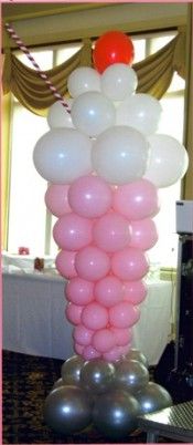 a bunch of balloons in the shape of a tower on top of a cake stand