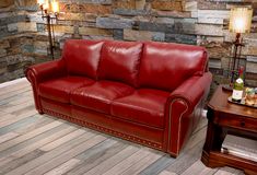 a red leather couch sitting on top of a hard wood floor next to a table