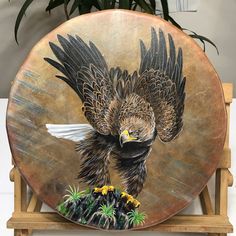 a painting of an eagle is shown on a wooden stand next to a potted plant