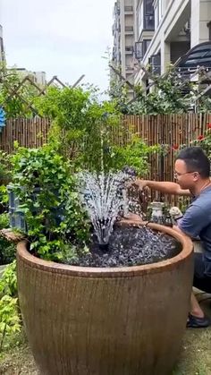 a man kneeling down next to a large potted planter filled with water and plants