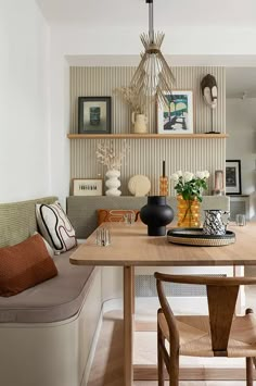 a dining room table with two chairs and a bench in front of it, along with pictures on the wall