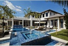 an outdoor swimming pool with lounge chairs and umbrellas next to the home's front yard