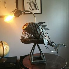 a fish lamp sitting on top of a wooden table next to a clock and pictures