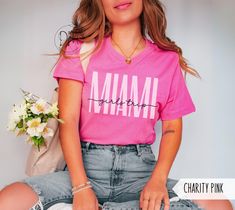 a woman in pink shirt sitting on the floor with her hand on her hip and flowers