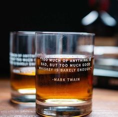 two glasses filled with whiskey sitting on top of a table