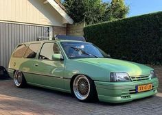 a green station wagon parked in front of a house