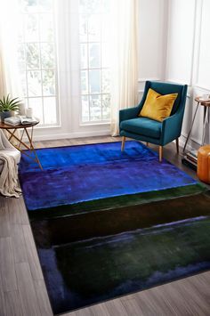 a living room area with a blue rug and green chair in front of a window