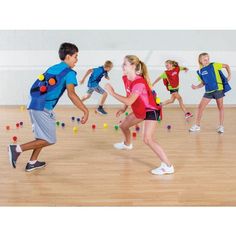 a group of young people playing with balls in an indoor gym area on a hard wood floor