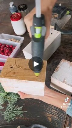 a person holding a piece of wood in front of some berries and other items on a table