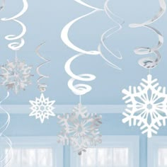 snowflakes and swirls hanging from the ceiling in a room with blue walls