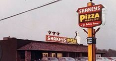 there is a restaurant called shakey's pizza parlor with cars parked in the lot