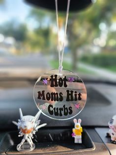 a glass ornament that says hot moms hit curbs on the dashboard