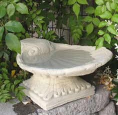 a white bird bath sitting on top of a stone slab