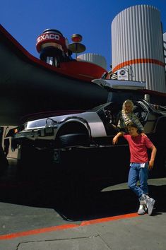 a woman and child standing in front of a large vehicle