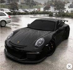 a black sports car parked in a parking lot on a rainy day with no one around