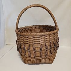 This vintage handwoven basket is a charming addition to any collection. Its Penobscot style features curly twist details that showcase the craftsmanship of its handmade construction. The basket is made from split ash and sweet grass materials, and its round shape and medium size make it perfect for storage or as a decorative piece. The body of the basket is about 9" tall by 11 1/4" in diameter. The handle extends up from the main body about 5 3/4" making it about 14 3/4" tall overall. Its tan and brown color adds a touch of warmth to any room. This original piece was made in the United States and is a great example of traditional American basket weaving. Curly Twist, Hand Woven Baskets, Basket Weaving, Round Shape, Brown Color, Medium Size, Decorative Pieces, Maine, Baskets