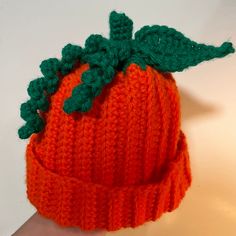 an orange knitted hat with green leaves on top