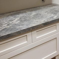 a kitchen counter top with white cabinets and drawers