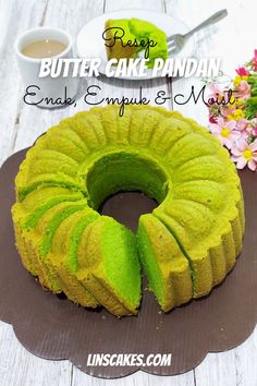 a bundt cake with green icing on a plate next to flowers and a cup of coffee