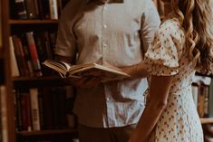 a man and woman standing next to each other in front of a bookshelf