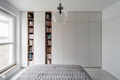 a bed sitting in a bedroom next to a book shelf filled with lots of books