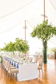 the tables are set up with white linens and greenery