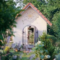 a small white building surrounded by trees and bushes