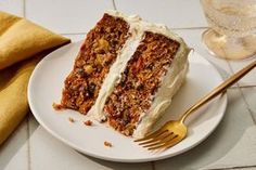 a piece of carrot cake on a white plate with a gold fork next to it