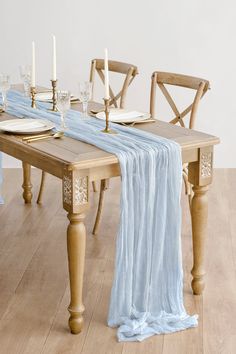 a wooden table topped with a blue cloth covered dining chair next to a white wall