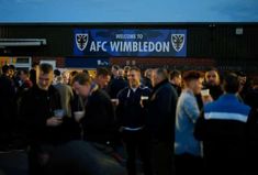 a group of people standing in front of a building with a sign that says ac wimbledon on it