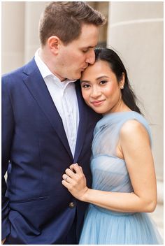 a man in a blue suit and woman in a light blue dress pose for the camera