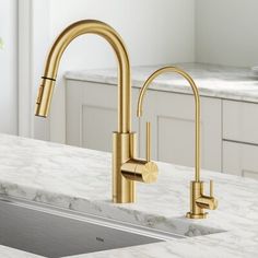 a kitchen sink with gold faucet and marble counter top